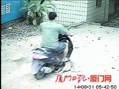 该男子得手后，将一条狗放在摩托车上拉走。